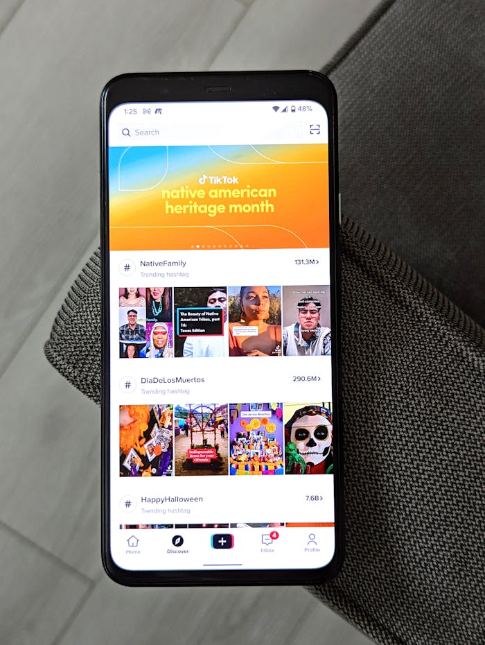 A smartphone showing TikTok trends for Native American Heritage Month, Dia De Los Muertos, and Halloween.